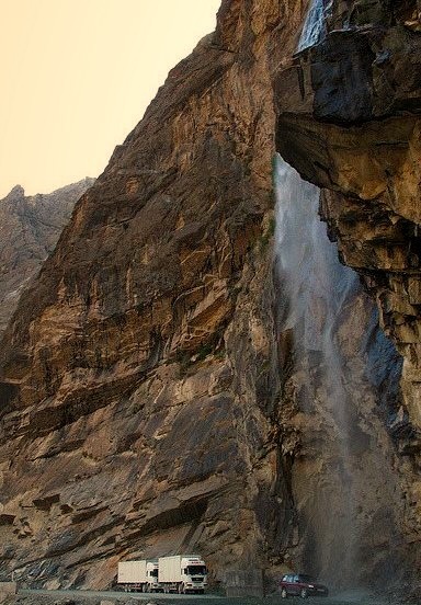 Waterfall washing all cars and trucks passing by a mountain road, Pamir Mountains, Tajikistan